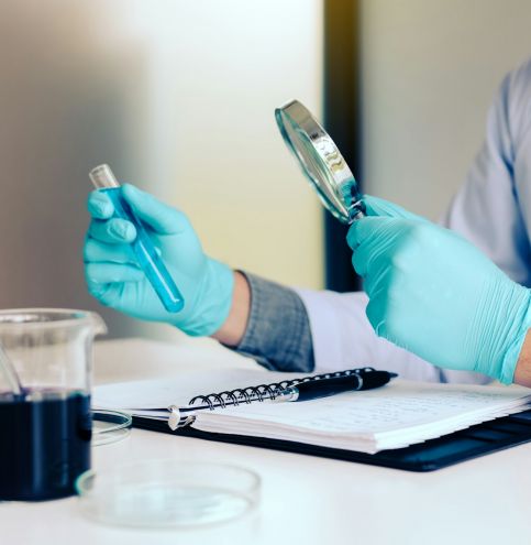 Chemist or scientist using magnifying glass dispense the solution in a glass jar.